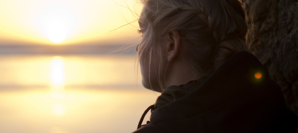 Mujer mirando el atardecer en el agua