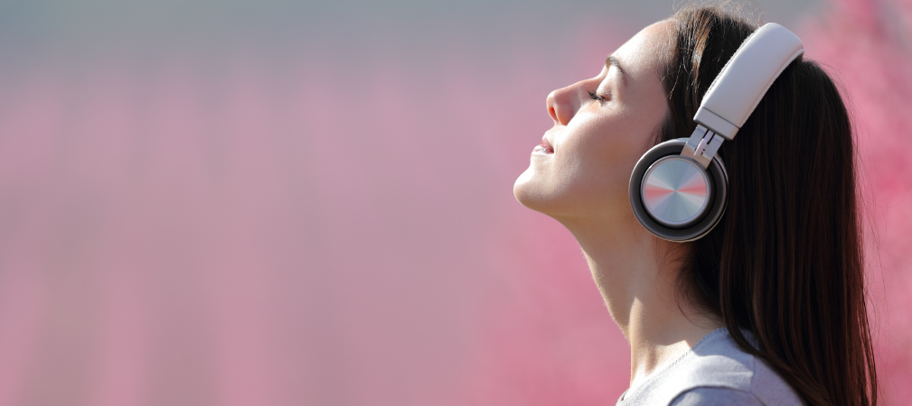 Mujer escuchando música relajada con fondo rosa