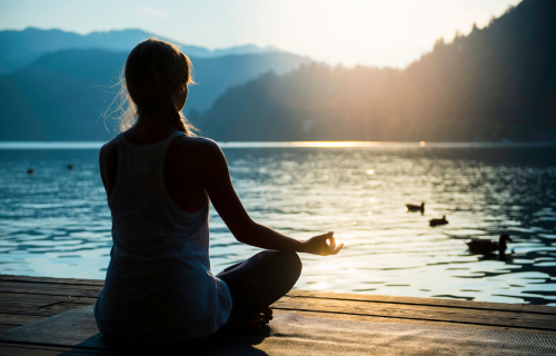 Mujer meditando frente al lago