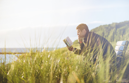 Hombre leyendo un libro entre la naturaleza